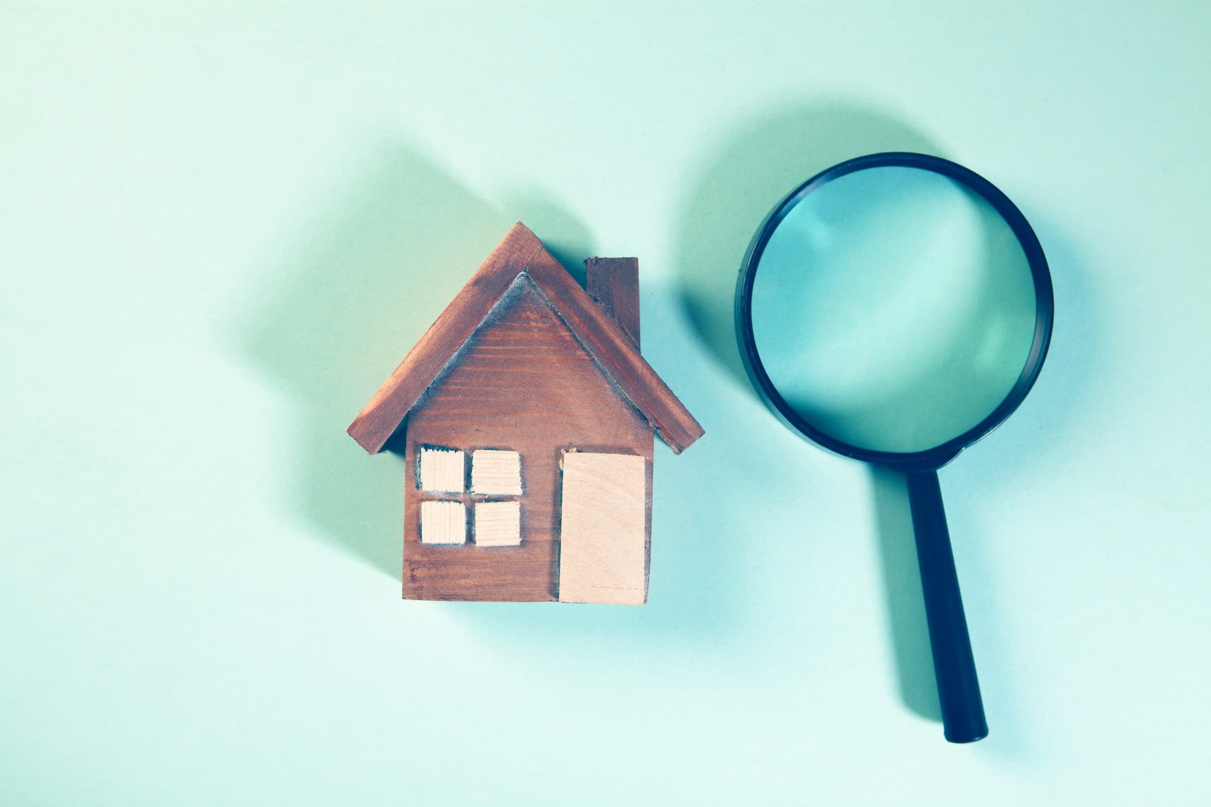 Magnifying glass next to a wooden house model